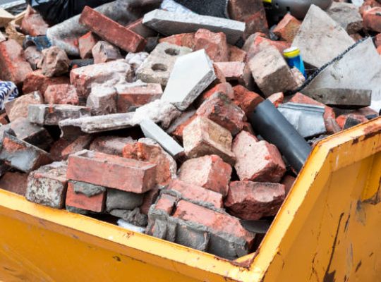 Yellow metal skip full of old bricks